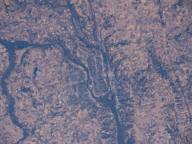 An areal photograph of an area with multiple rivers, human settlement, and agricultural fields.