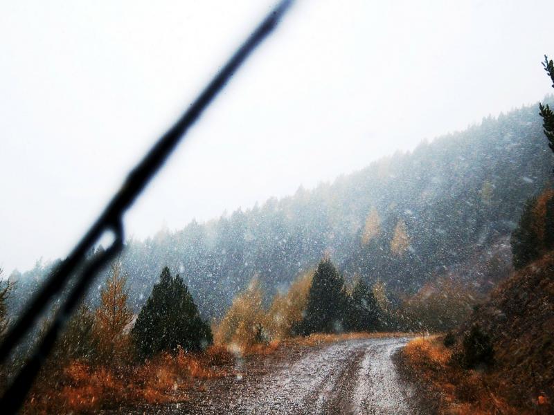view through a car windshield of snow on a dirt mountain road
